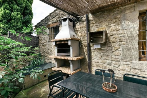 Patio rústico de piedra en Can Gat Vell B&B en Girona con parrilla exterior, mesa de comedor y exuberante vegetación