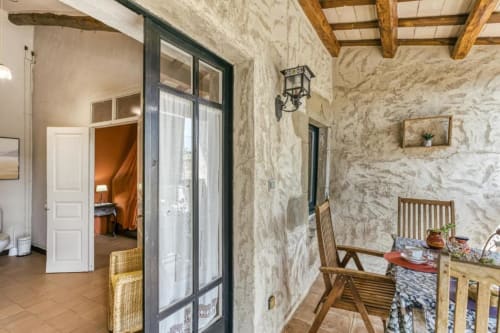Interior rústico de piedra en la casa rural Can Gat Vell en Girona con vigas de madera, suelos de barro y muebles tradicionales