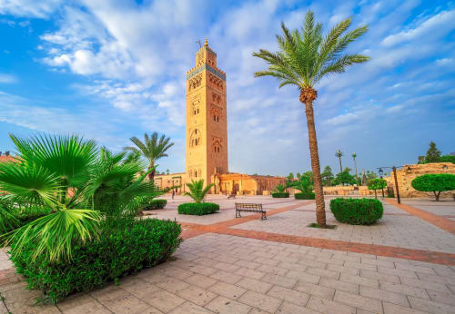 Koutoubia Mosque minaret in Marrakech with palm trees and paved plaza near Riad Madinina
