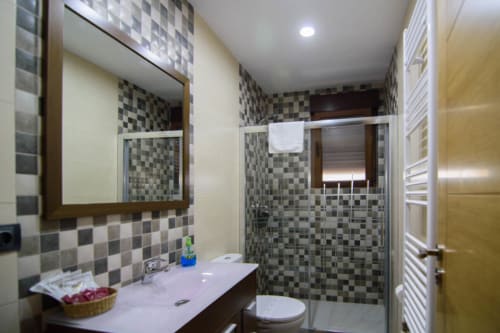 Baño moderno en Tradición Rural de Nieva con azulejos de cuadros, lavabo, inodoro, ducha y toallero climatizado