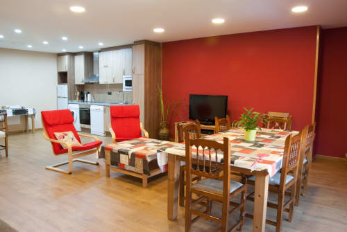 Luminosa sala común en Tradición Rural con paredes de acento rojo, mesa de comedor de madera, sillones rojos y cocina en Nieva