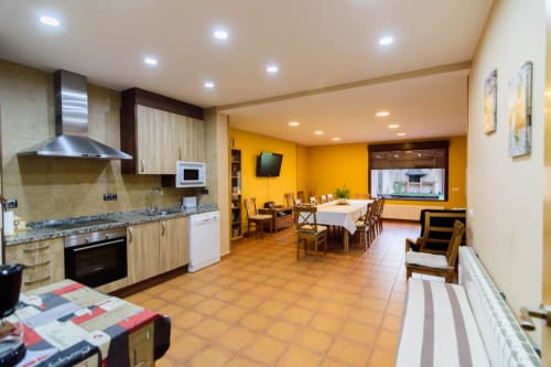 Amplia zona cocina-comedor en Tradición Rural de Nieva con paredes amarillas, azulejos de barro y muebles de madera.