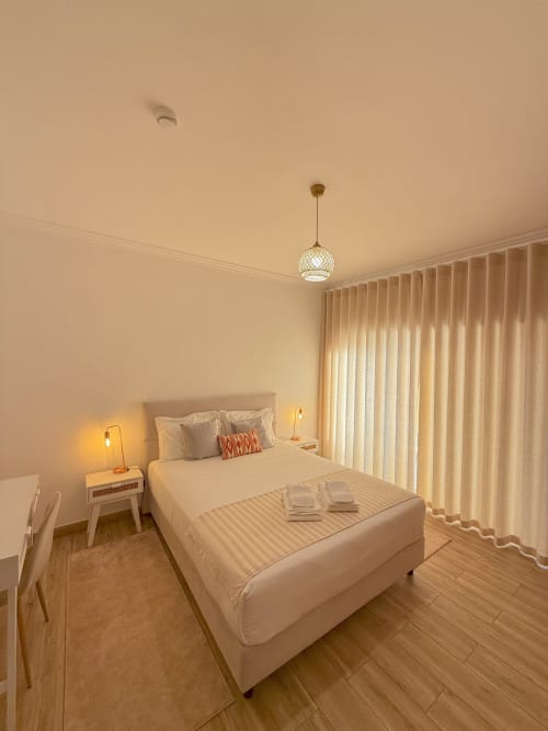 Modern double bedroom at Embaixada da Vila, Cascais with white bedding, pendant light, and floor-to-ceiling curtains