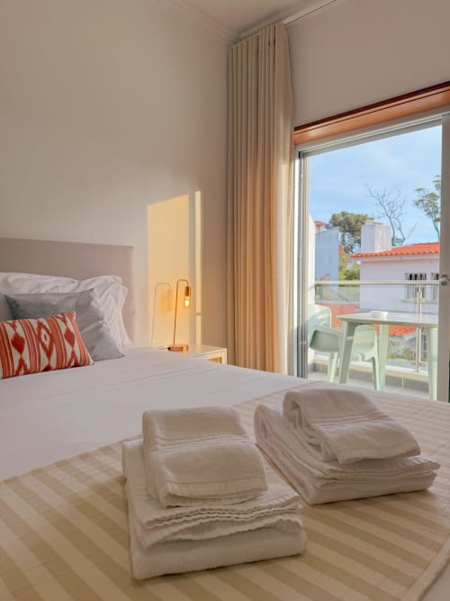 Bright bedroom at Embaixada da Vila in Cascais with double bed, fresh towels, garden view balcony, and natural light