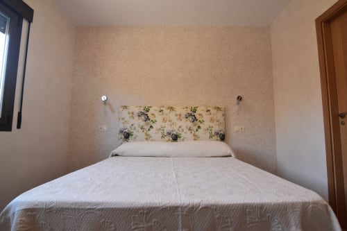 Acogedora habitación en hotel Tradición Rural de Nieva con cabecero floral y ropa de cama blanca