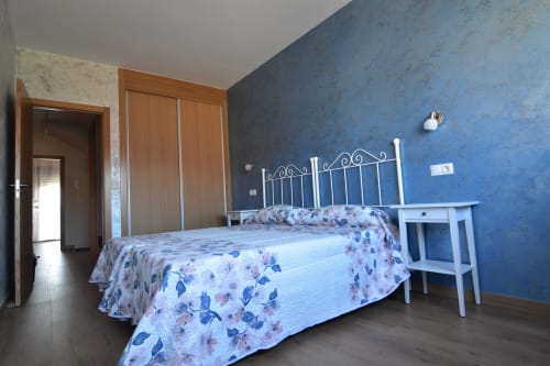 Habitación en Tradición Rural con paredes azules, cama de hierro blanco y ropa de cama floral en Nieva, España