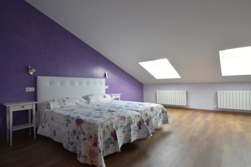 Dormitorio moderno en Tradición Rural con pared acentuada en púrpura, cama queen, tragaluces y piso de madera en Nieva