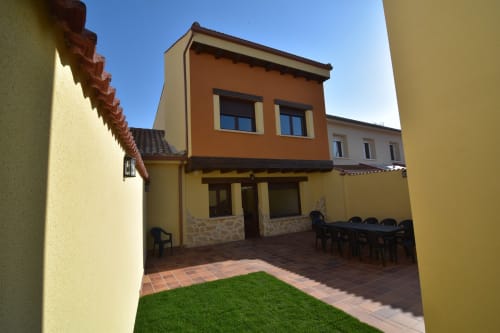 Patio tradicional rural en Nieva con edificio naranja, terraza y césped verde