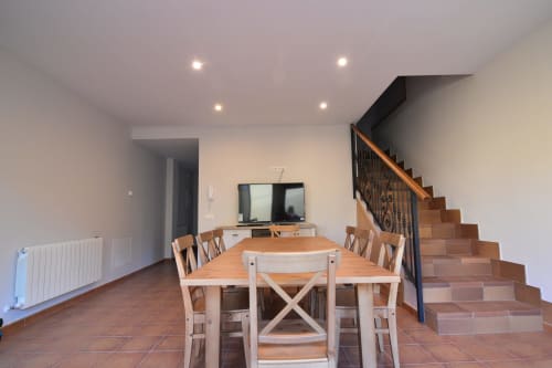 Comedor con mesa y sillas de madera, televisor, escalera y radiador en la propiedad Tradición Rural, Nieva