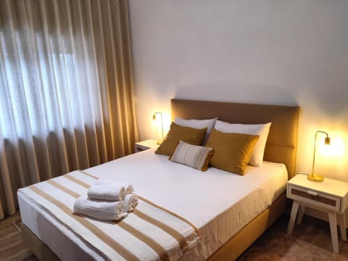 Elegant double bedroom at Embaixada da Vila in Cascais with golden headboard, white linens, and warm ambient lighting