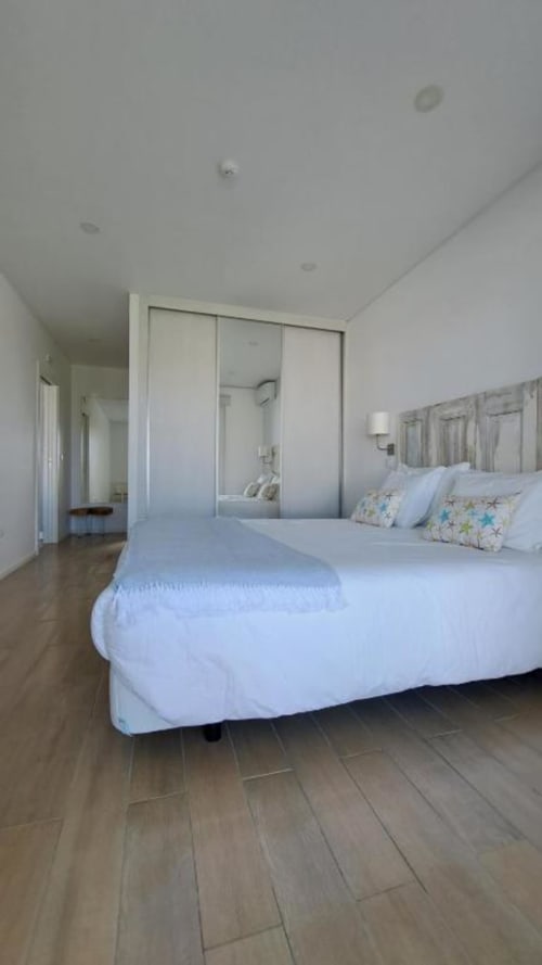 Bright modern bedroom at Recantus Comporta with white bed, mirrored wardrobe, and wooden flooring