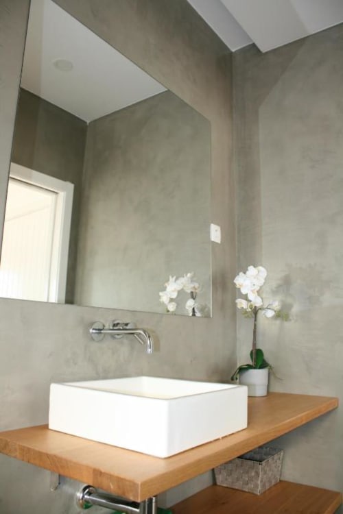 Modern bathroom at Recantus Comporta with white vessel sink on wooden vanity, large mirror, and white orchid decor