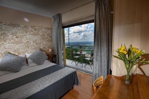 Elegante camera dell'Hotel Vista Lago a Brunate con balcone vista lago, letto blu, fiori gialli e paesaggio montano