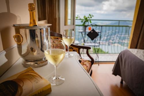 Flute di champagne e bicchieri di vino sul balcone con vista sul lago dell'Hotel Vista Lago, Brunate Italia