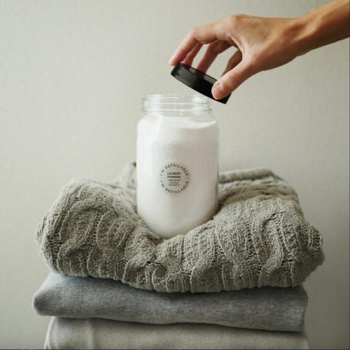 Hand holding laundry powder jar over folded towels at Villa Várzea, Várzea Portugal bed and breakfast