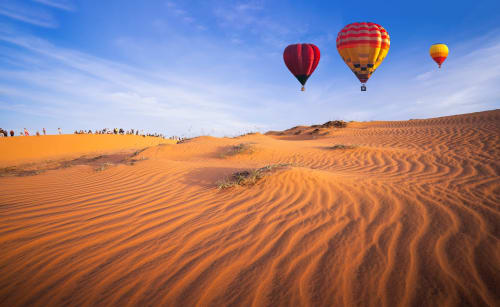 Hot air balloons floating above golden sand dunes near Marrakech, Morocco at Riad Madinina