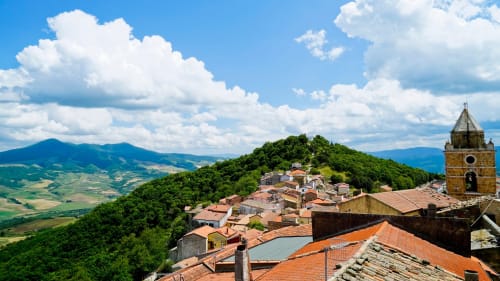 Antico borgo medievale di Vallata con tetti in cotto, campanile e paesaggio verde collinare