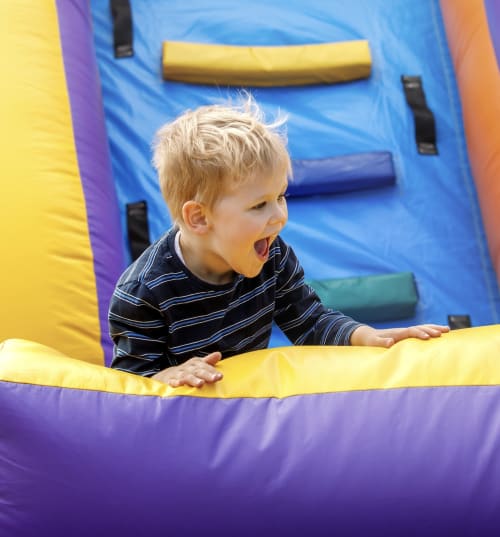 Niño pequeño jugando en una casa inflable multicolor en Tradición Rural, alojamiento familiar en Nieva, España