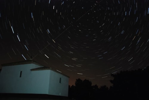 Fotografía de rastros de estrellas sobre edificio blanco en Tradición Rural de Nieva, España de noche