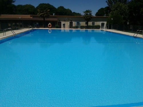 Piscina cristalina en Tradición Rural, hotel rural en Nieva, España, rodeada de frondosa vegetación e instalaciones