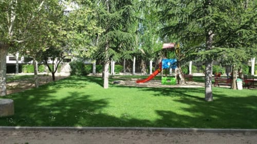 Parque verde del hotel Tradición Rural en Nieva con árboles frondosos, tobogán, bancos y jardín bien mantenido