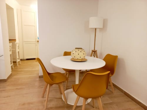 Moderna sala da pranzo con tavolo rotondo bianco, sedie giallo senape e lampada da terra a La Suite del Giardino, Napoli