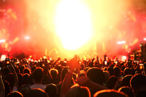 Vibrant concert crowd at music festival with red stage lighting and raised hands