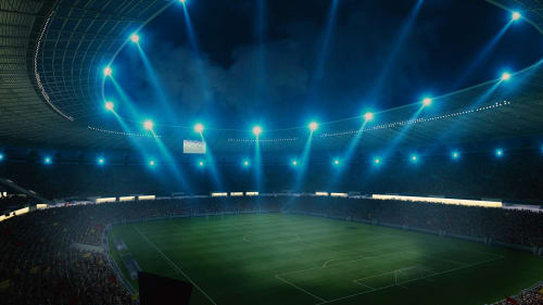 Illuminated football stadium at night with packed crowds and bright floodlights