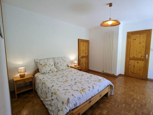 Chambre spacieuse aux Chambres d'hôtes le Grand Bienfaisy à Remiremont avec lit en bois, vue sur le jardin et parquet.