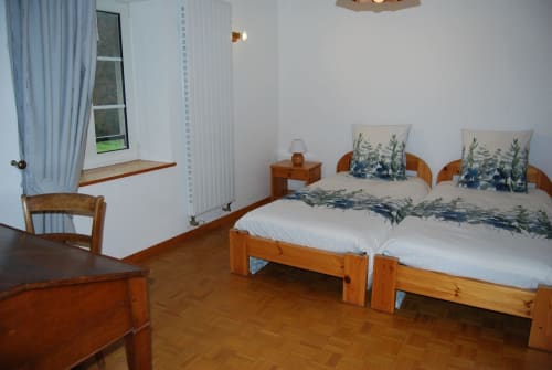 Chambre spacieuse aux Chambres d'hôtes le Grand Bienfaisy à Remiremont avec lits jumeaux, mobilier en bois, vue sur le jardin