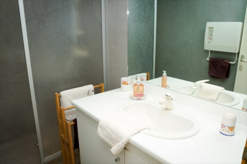 Vasque blanche, miroirs et articles de toilette dans la salle de bain de Chambres d'hôtes le Grand Bienfaisy à Remiremont