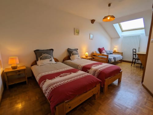 Chambre spacieuse sous les toits aux Chambres d'hôtes le Grand Bienfaisy à Remiremont avec deux lits en bois, éclairage chaleureux et