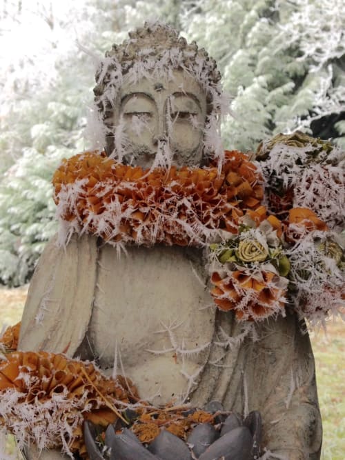 Frost-covered garden statue with orange flowers at Domaine de l'Ocrerie in Pourrain, France
