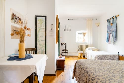 Habitación familiar luminosa en Can Gat Vell B&B en Girona con dos camas, ventana, suelos de madera y adornos decorativos azules