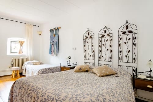 Dormitorio luminoso en Can Gat Vell B&B en Girona con dos camas, cabeceros de metal decorativo y mobiliario rústico.