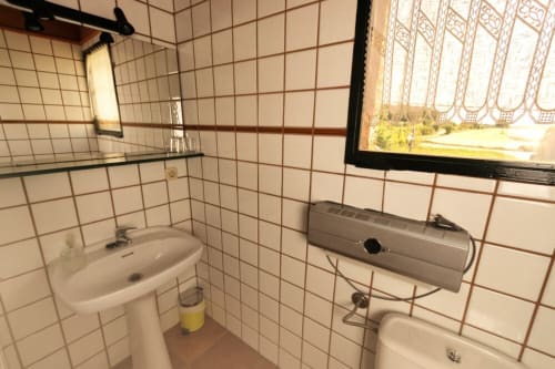 Baño con azulejos blancos, lavabo, calentador de agua y ventana con vistas al jardín en Can Gat Vell en Girona