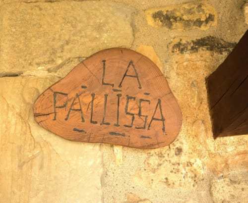 Letrero de madera que dice 'LA PALLISSA' en pared de piedra color terracota en la casa rural Can Gat Vell en Girona, Cataluña