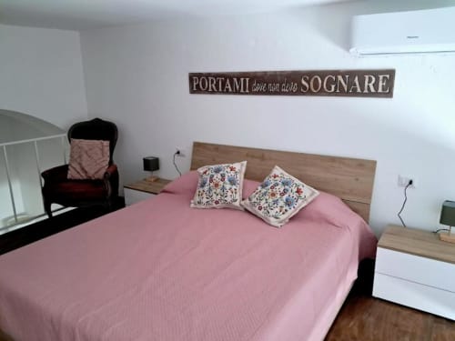 Camera da letto rosa con cuscini floreali e testata in legno a La Suite del Giardino, Napoli