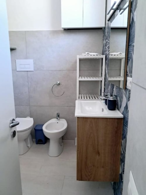 Bagno moderno di La Suite del Giardino a Napoli con WC, bidet, lavabo e scaffali bianchi