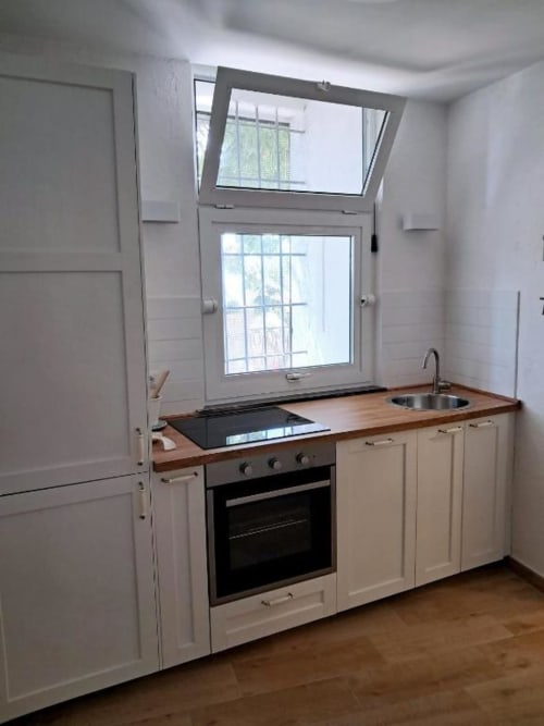 Cucina moderna con mobili color panna, piano in legno, forno integrato e ampie finestre con vista sul giardino