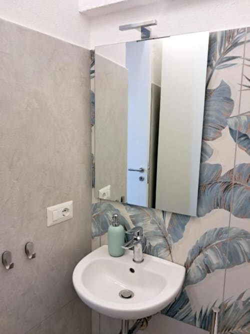 Bagno moderno de La Suite del Giardino a Napoli con lavabo rotondo, specchiera e piastrelle con motivi botanici