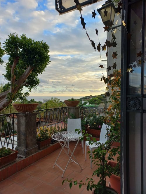 Terrazza con vista mare di La Suite del Giardino, Napoli. Arredamento bianco, piante in vaso e decorazioni stellari affacciate sul