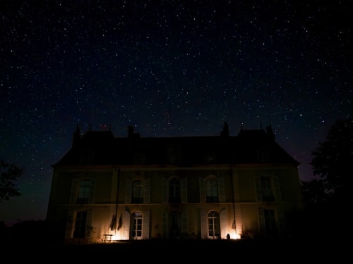 Château de Vaux Morvan illuminated at night under starry sky in Étang sur Arroux, France