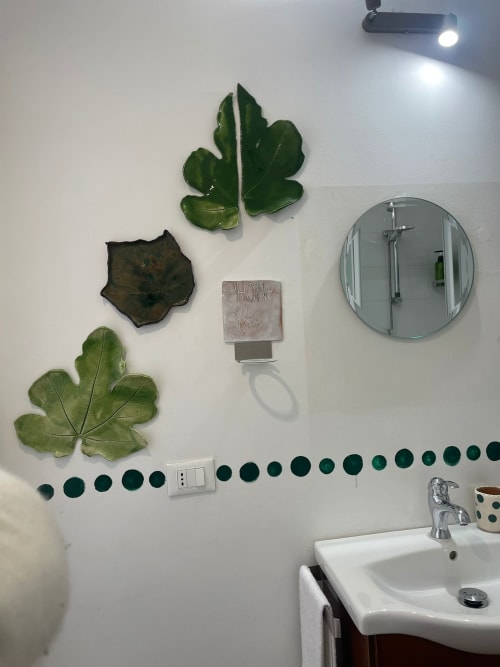 Bathroom wall decor at La Cascina di Bea with pressed green leaves, circular mirror, and pendant lights above sink