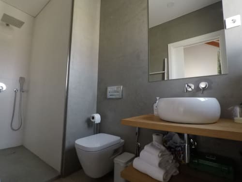 Banheiro moderno no Apartamento Flamingo em Recantus Comporta com sanitário suspenso, cuba de apoio, espelho e área de duche
