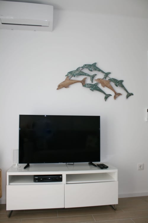 Recantus Comporta Dolphin Apartment with flat-screen TV, white media console, and decorative fish wall art above.