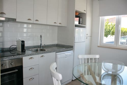 Cozinha moderna branca do Apartamento Dolphin em Recantus Comporta, Comporta, com eletrodomésticos em aço inoxidável e área de refeições