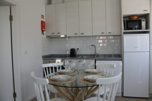 Cozinha e sala de jantar modernas no Apartamento Dolphin em Recantus Comporta com armários brancos, backsplash de azulejos cinzentos e