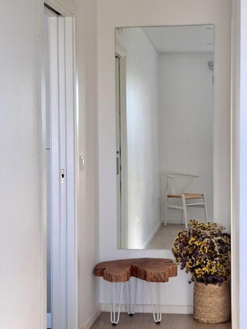 Bright entryway at Recantus Comporta with mirror, wooden stool, dried flowers in basket, and open door to bedroom
