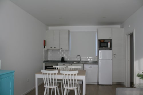 Modern kitchen with white cabinetry, island seating, and dining area at Recantus Comporta's Egret Apartment in Comporta